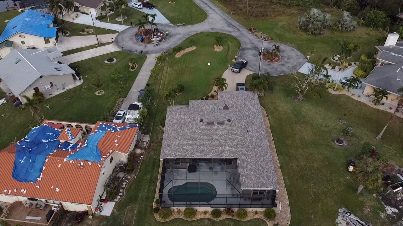 Storm-response tarping across a Florida neighborhood after hurricane damage